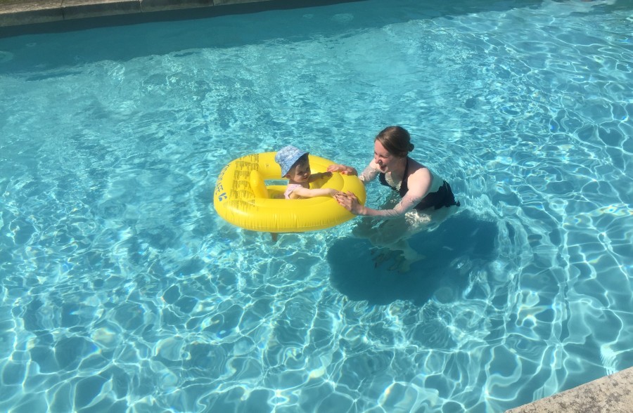 Woman and child in floating aid in swimming pool
